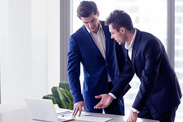 imagem de dois homens de pé em frente a um computador